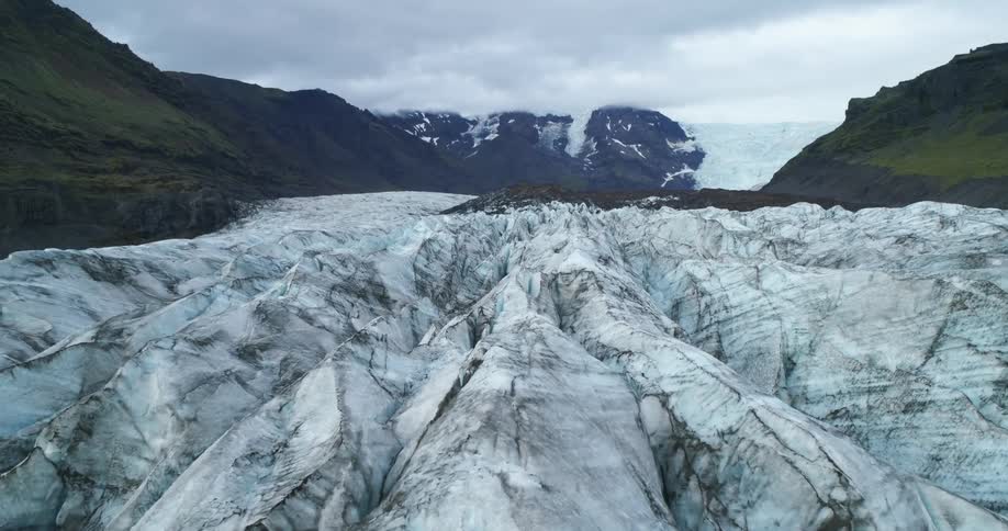Glaciers of ice with a mountain range the sky and clouds in the background