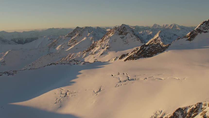 Snow covered mountain range sits against hazy horizon