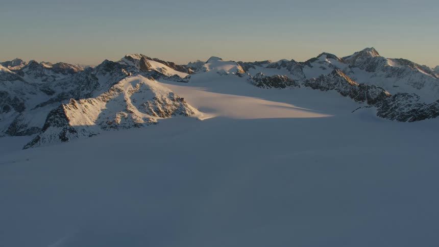 An aerial view of a mountain range and the Brandenburger Haus covered in snow