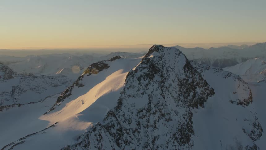 Sun highlights portions of snow covered mountain range leaving the majority in shadow