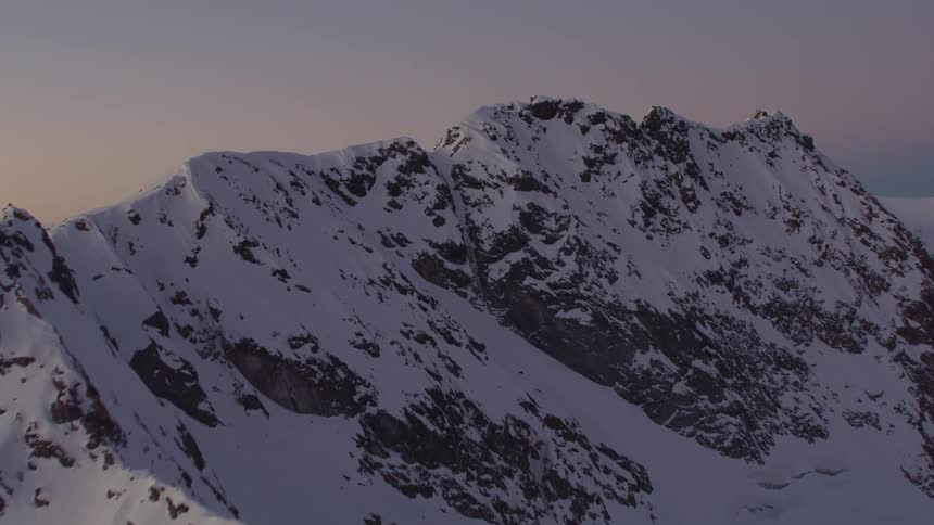 A snowy mountain range in the evening