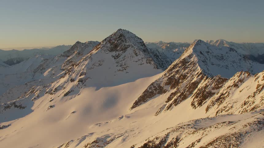 Sun shining on the sides of snowy mountains in the wilderness