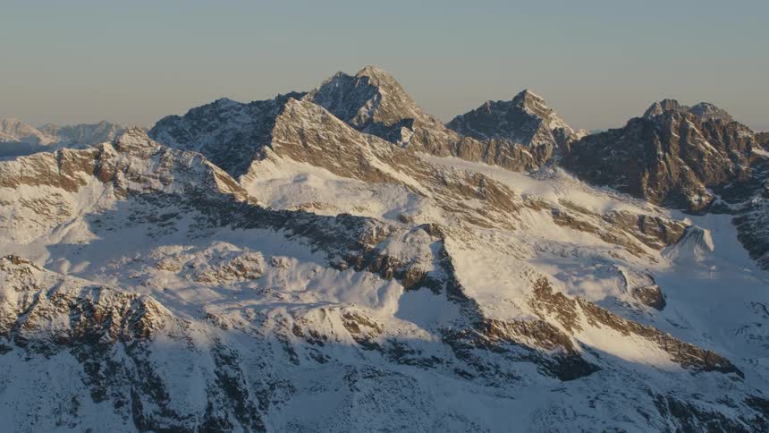 A mountain range covered in snow and ice with the sky and clouds in the background