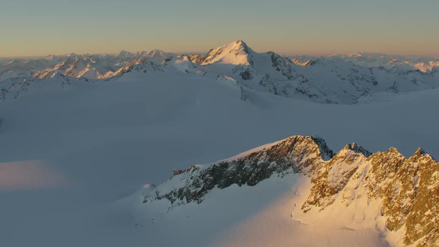 A mountain range covered in thick snow in the evening