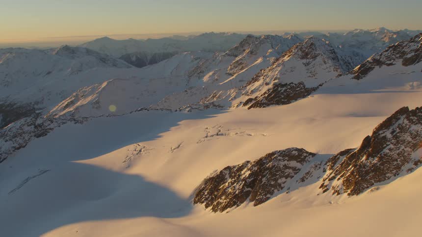 Snow covers mountain range on hazy day under red tinted sky