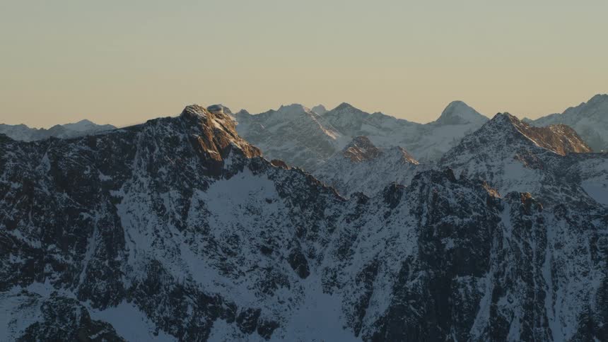 Sunlight touches peaks of snow covered mountain on hazy day