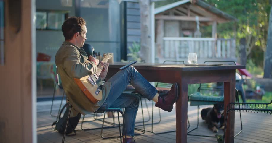 A man sitting on a patio playing guitar