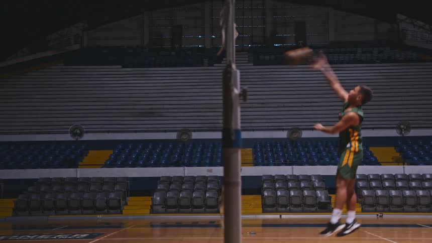 A man spikes the volleyball in the gym