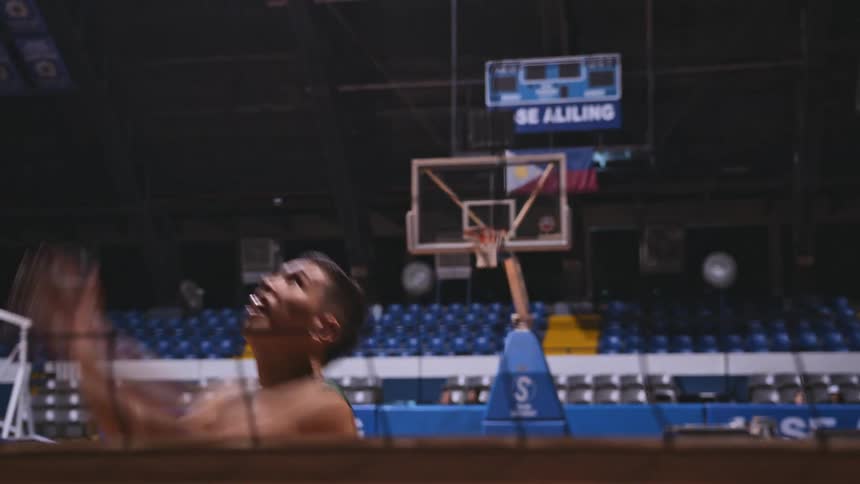 Male athlete practices with volleyball in basketball stadium