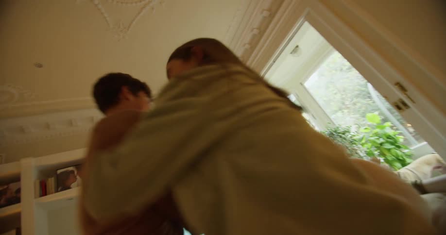Teenagers are jumping around on a couch having a pillow fight