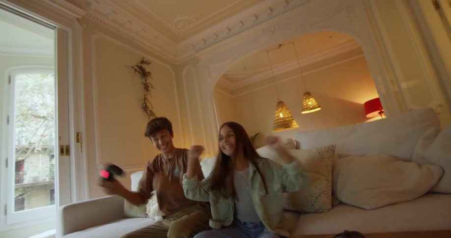A boy and girl are playing a video game in a living room and celebrating