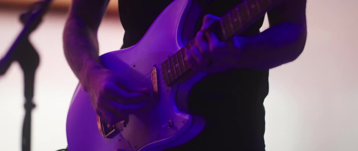 A man is in front of a microphone playing an electric guitar