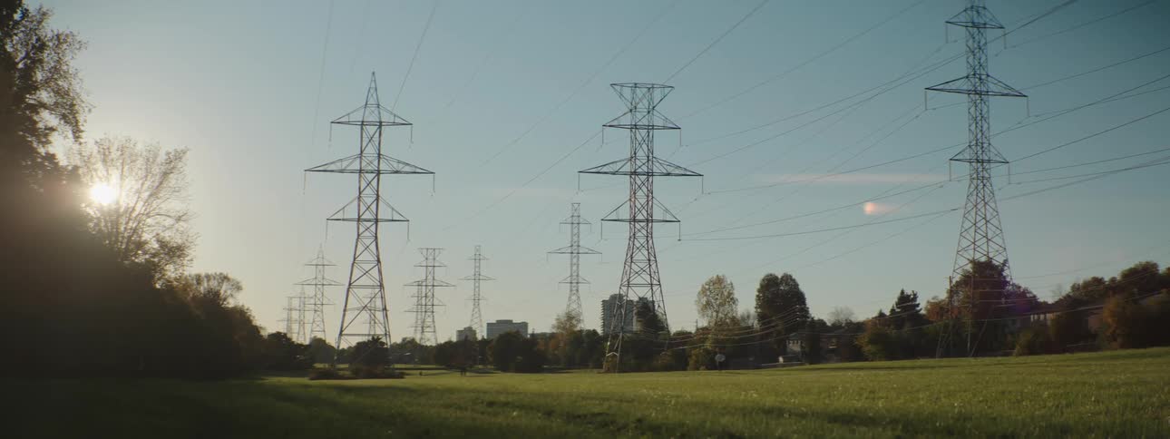 A person walks in the far distance in a field with several power lines