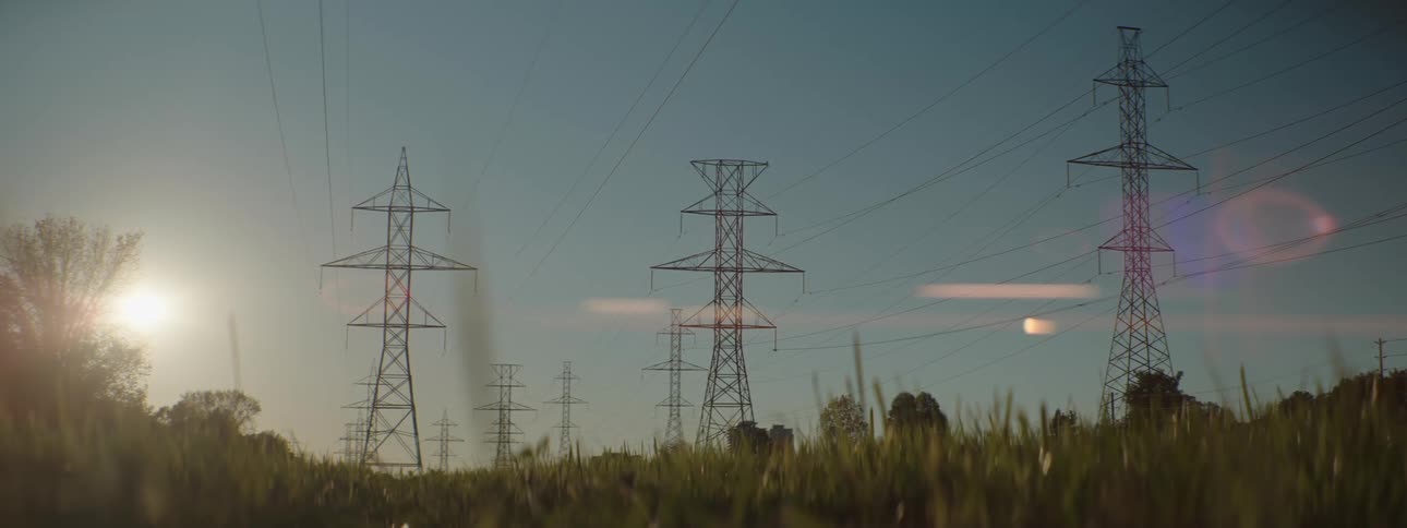 Power lines run across multiple transmission towers in a field