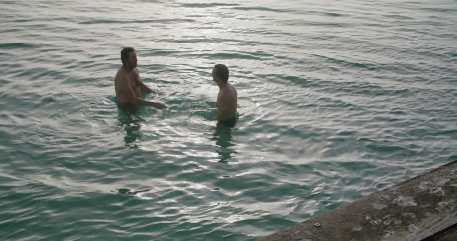 Two men swimming in sea giving handshake in the coast