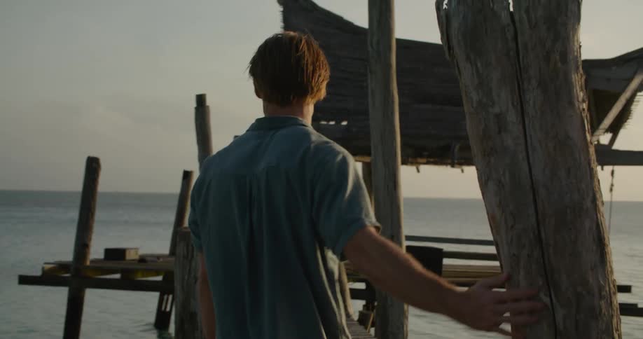 Man walks down pier smiling as he looks out to sea