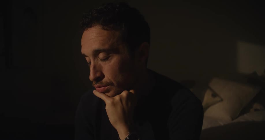 Man sits in dim room downcast his head propped on his hand