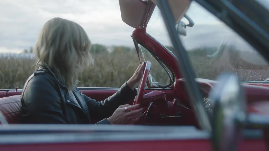 A woman driving off in a convertible