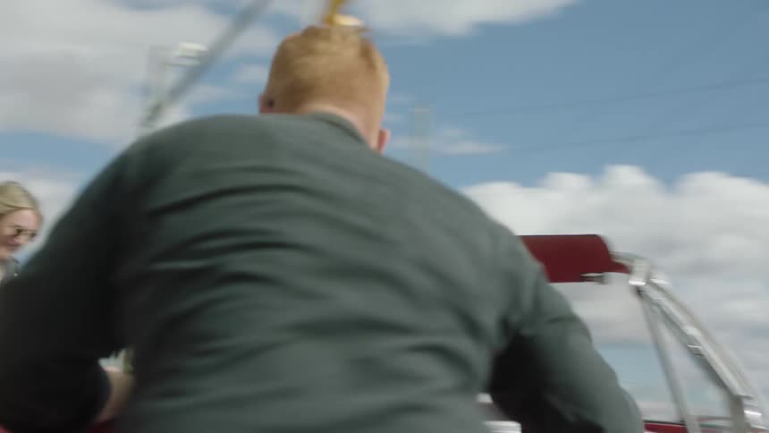 Man and woman get out of convertible parked at red light with top down and run around car before getting back into car