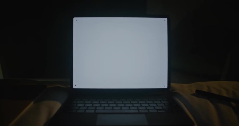 A laptop is on in the dark room