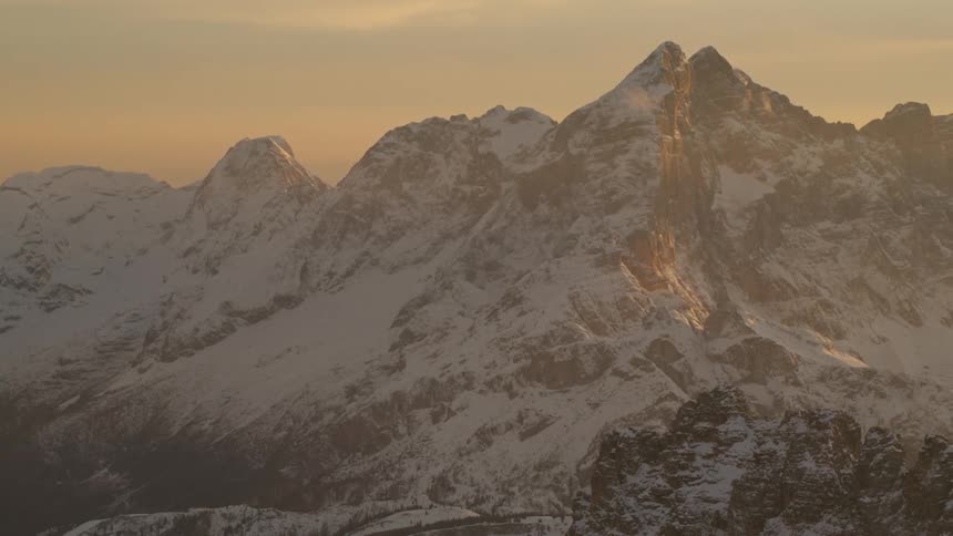 A snow covered mountain range as the sun sets