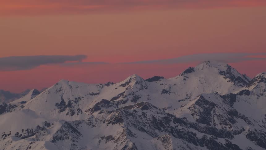 Snow covered mountains high in a pink sky