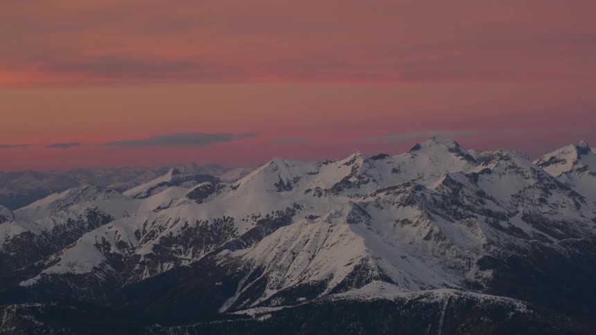 Snow covered mountains stand under red sky