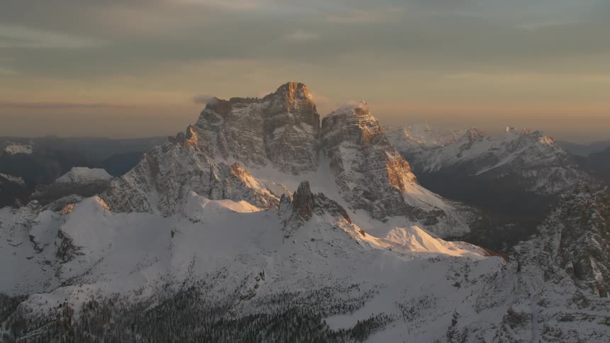 An aerial view of a landscape of snowy mountains in the evening