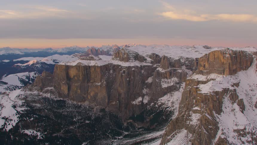 Snow covered rock formations and a mountain range on the horizon under a cloudy sky