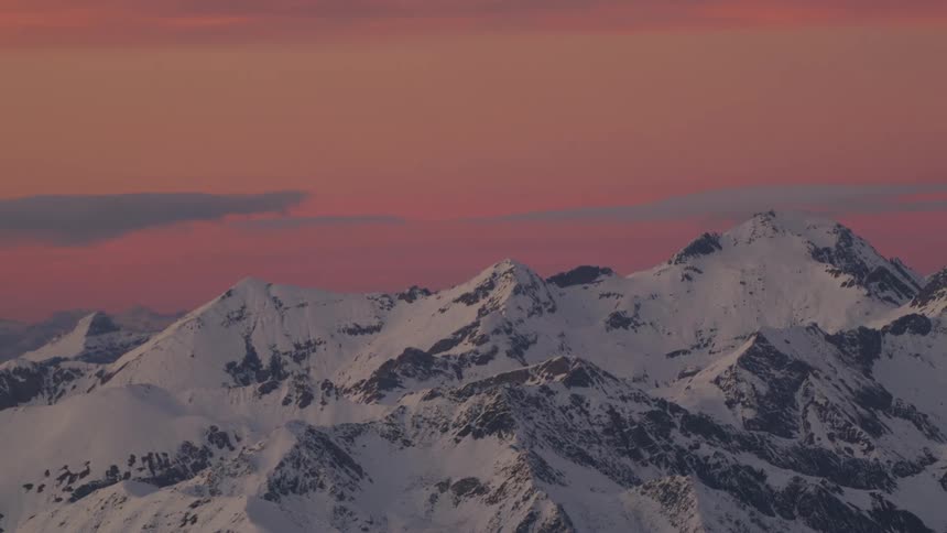 The sun sets over a snow covered mountain