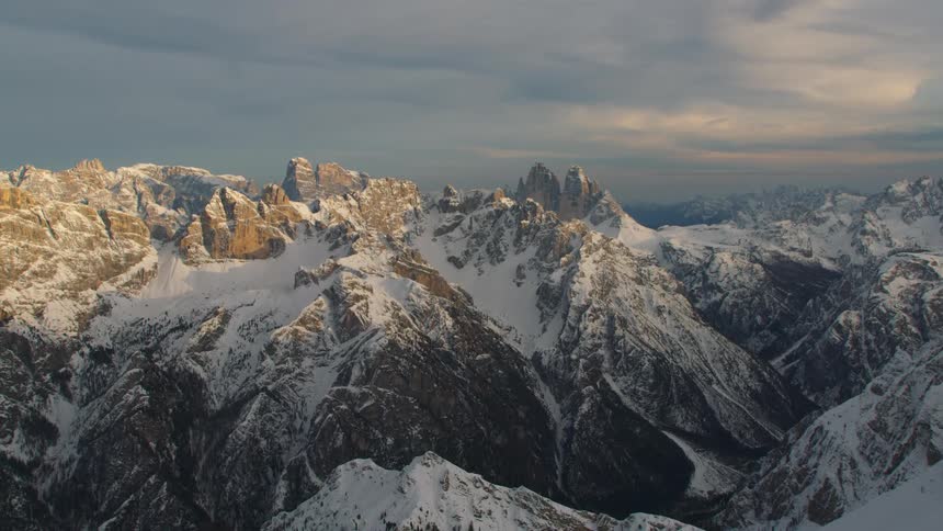 Snow covered mountains with peaks high in a cloudy sky