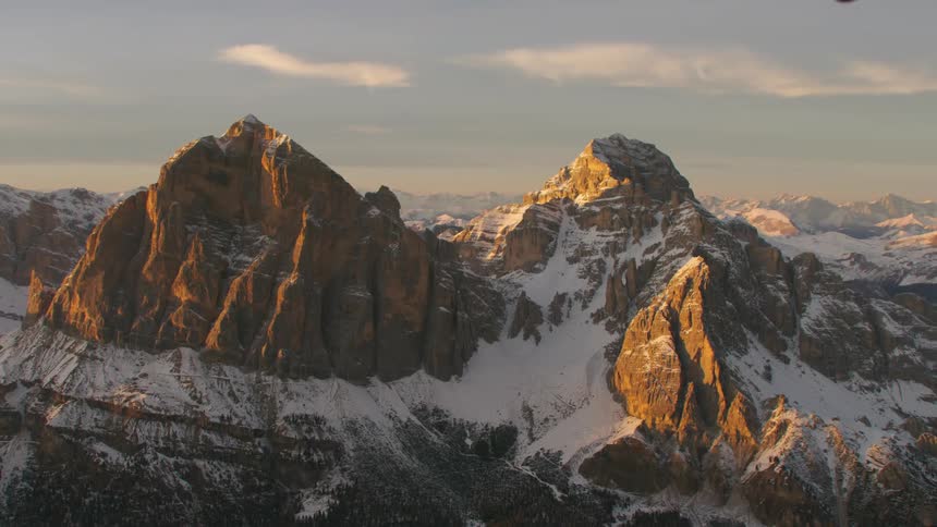 An aerial view of a rocky mountain landscape with snow in the evening