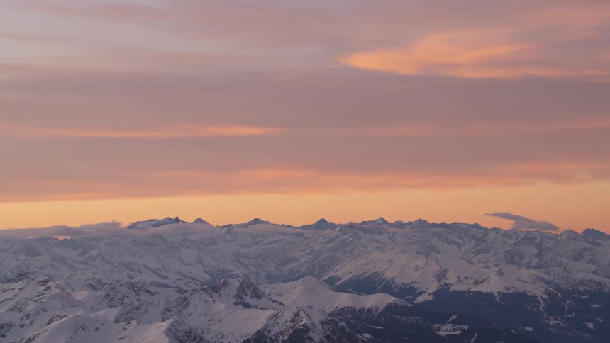A snow covered mountain range as the sun sets