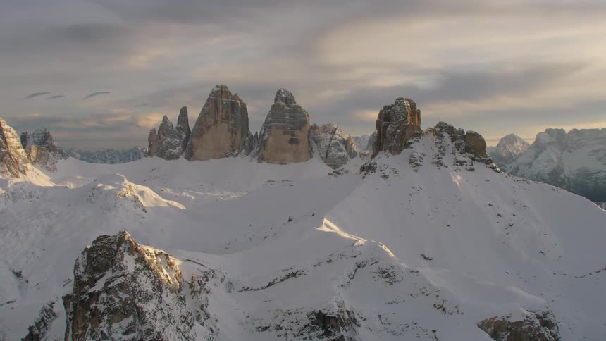 Tall jagged crags are standing up out of snow covered mountain wilderness