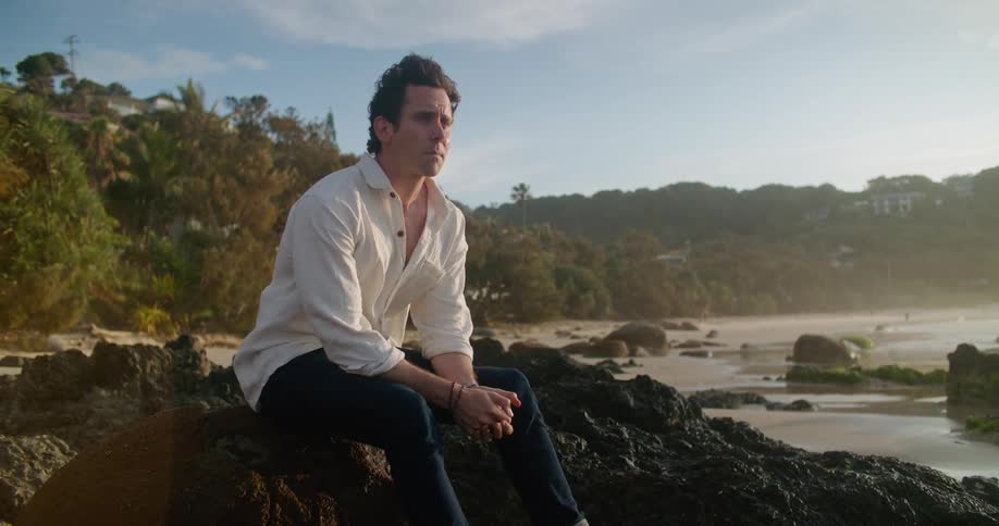 A man sits on rocks on the beach