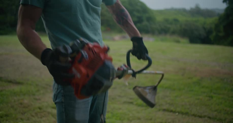 A man aggressively pulls the cord of a gas powered trimmer trying to start it