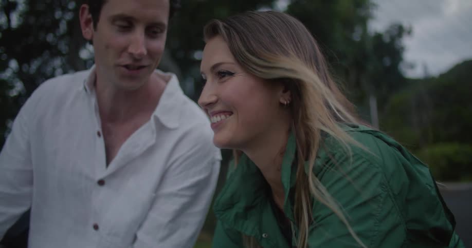 A man and woman talk and smile outside