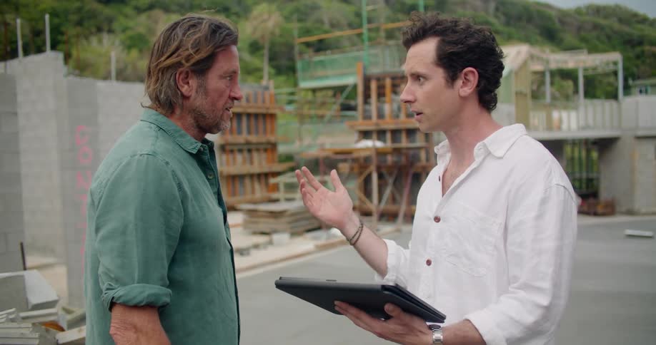 Two men on building site referring to tablet