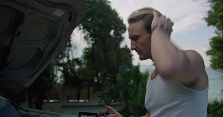 A man takes a wrench and works on the car engine