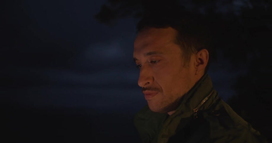A man standing outdoors and waving into the distance