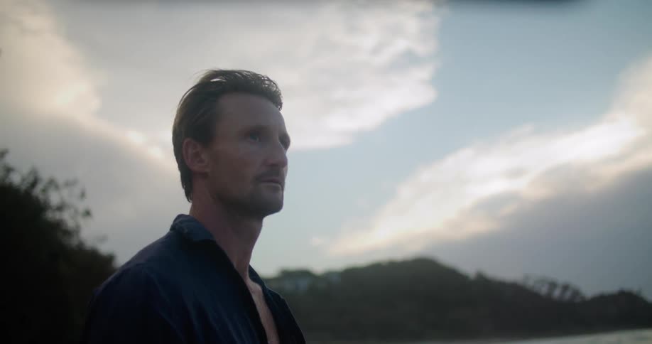 A man standing on a beach looking out at the ocean