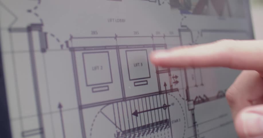 A person is scrolling on a laptop with their finger looking at building plan drawings