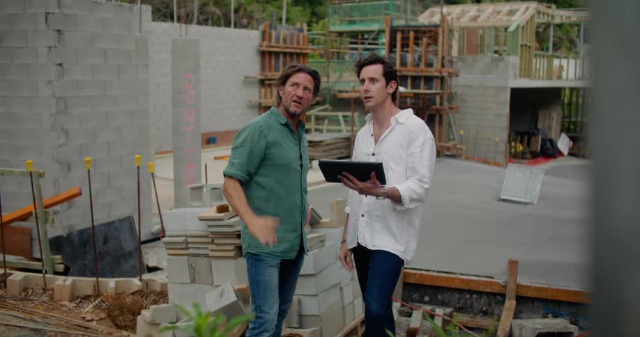 Two men look through a tablet while at a construction site
