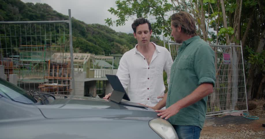Two men are standing by the construction site looking at a tablet