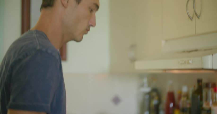 A man standing at the stove stirring and shaking the food in a pan
