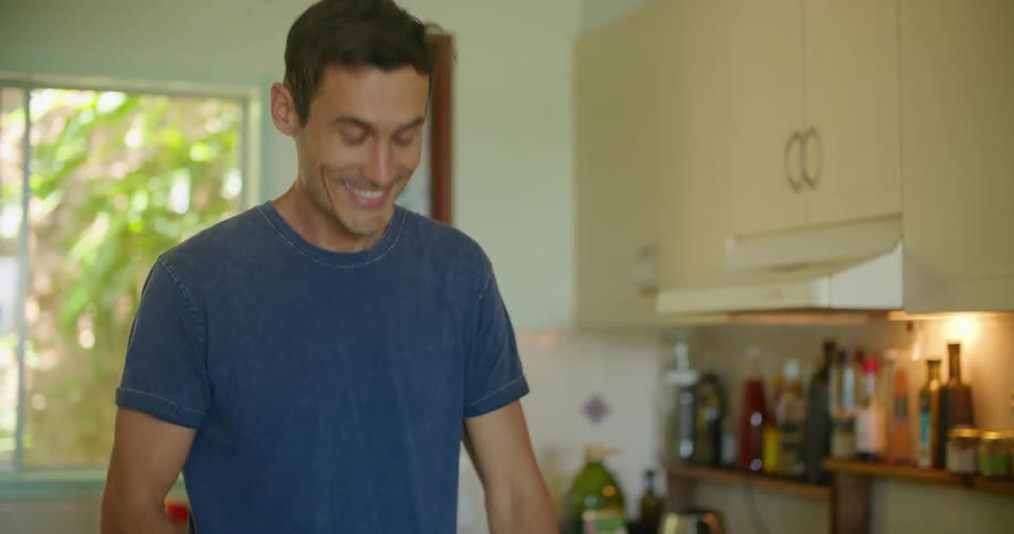 Young male couple smelling herbs while cooking at home