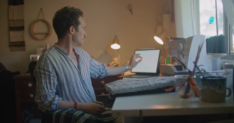 A man sitting in an office relaxing and using a tablet