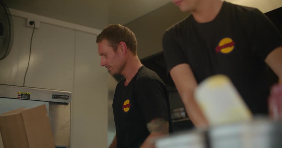 Two cooks working on the kitchen of a food truck organizing supplies