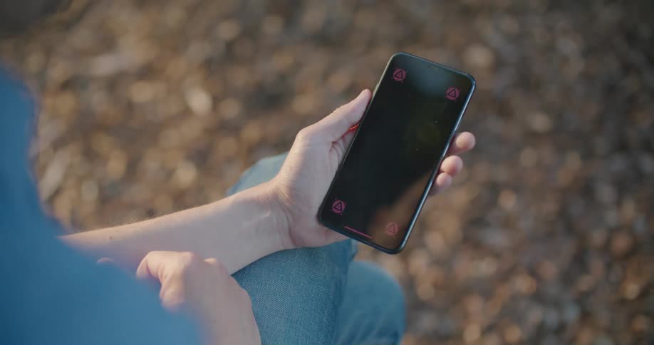 Man with blue shirt and jeans touches the screen of a smartphone