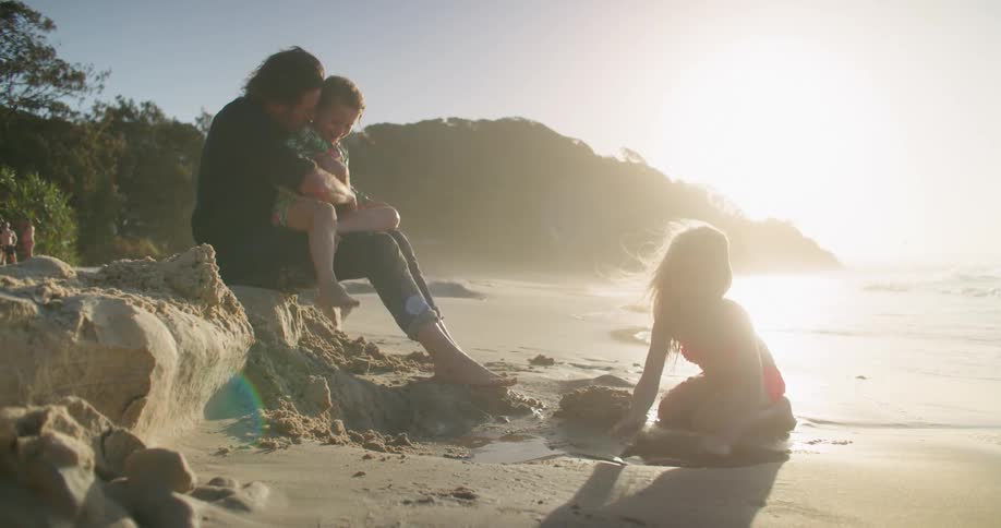 A father and his daughters playing at the beach